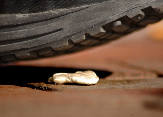 A shoe about to step onto discarded chewing gum on paving